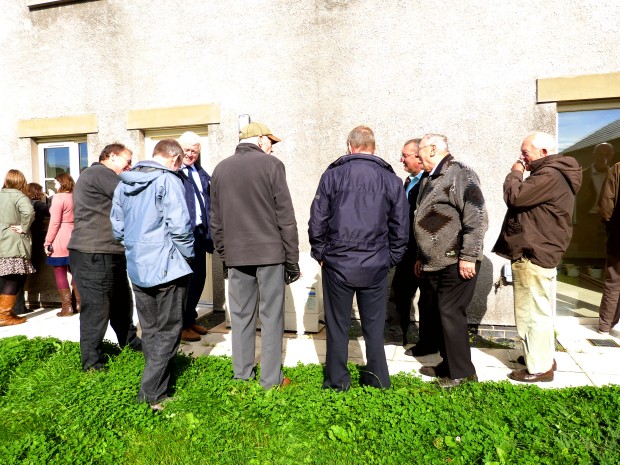 EDC PAC Planners admiring an exterior-mounted intake unit for a Mitsubishi Air-source heat pump at The Lyvennet Community Trust's Stoneworks Garth development in Crosby Ravensworth.